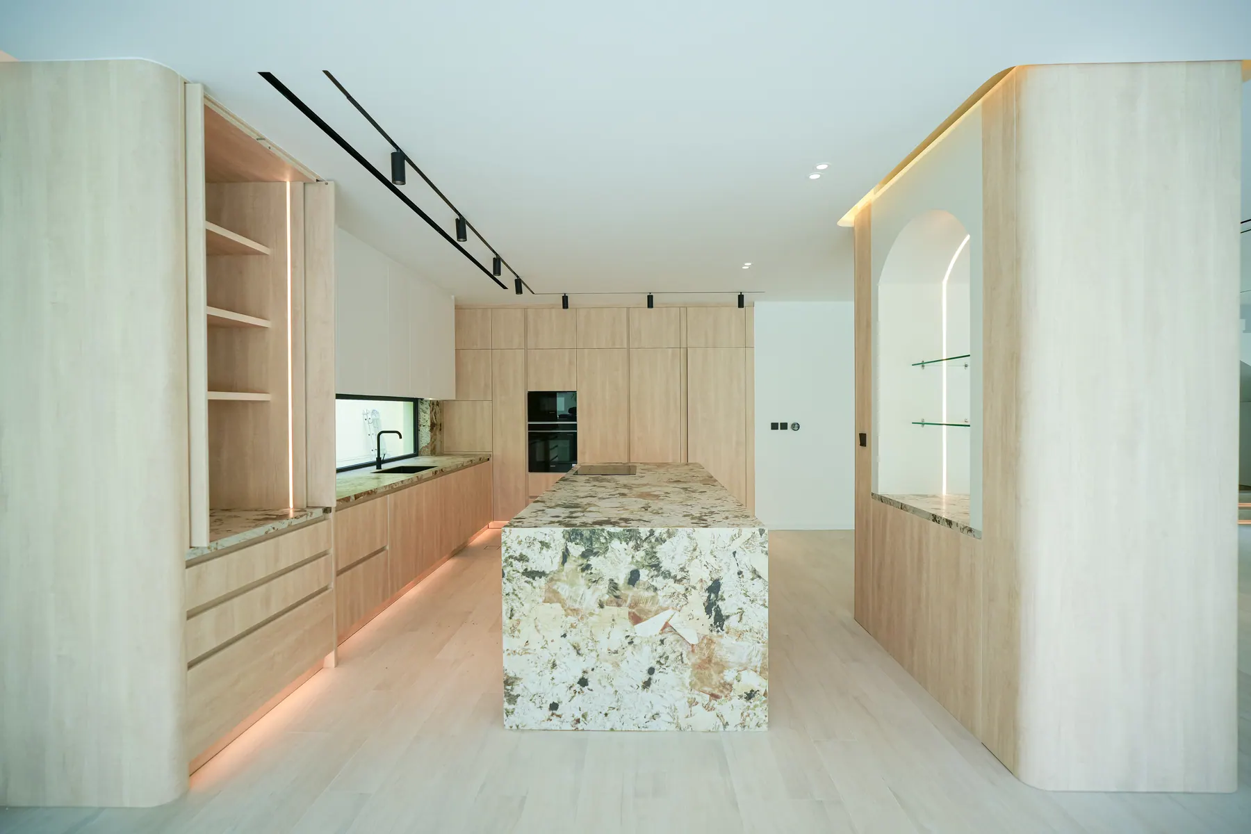 Open-plan kitchen in pale oak with a book-matched granite island