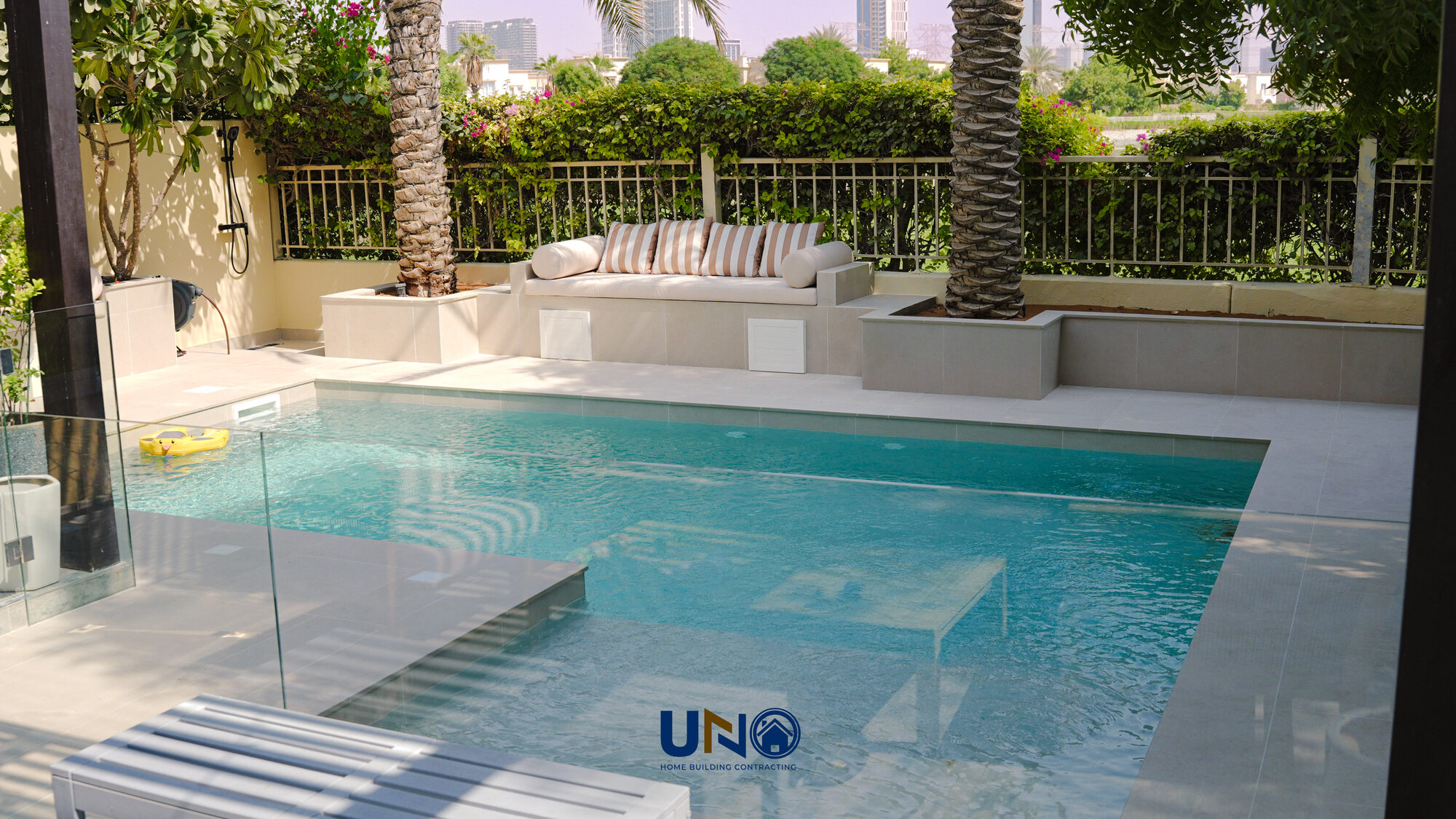 New swimming pool with glass fencing and mature planting in The Springs